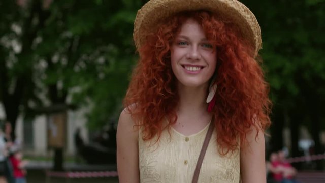Portrait of a red haired young smiling woman walking in the city streets smile happy slow motion summer face technology casual caucasian female beautiful lady outdoor closeup cute emotion posing