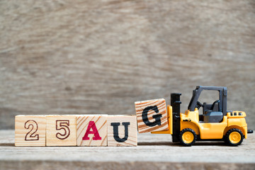 Toy forklift hold block G to complete word 25 aug on wood background (Concept for calendar date in month August)
