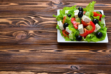 Greek salad on a wooden background. Space for text or design.