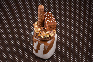 Chocolate extreme milkshake with brownie cake, chocolate paste and sweets. Crazy freakshake food trend. Copy space