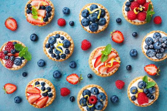 Naklejki Colorful berry tartlets or cake for kitchen pattern. Pastry dessert from above.
