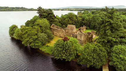 Fototapeta na wymiar Aerial image of the ruins of Inchmahome Priory on a tree covered island on the picturesque Lake of Menteith.
