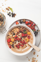 Smoothie bowl with banana, cocoa, berries and homemade granola, top view. Healthy vegan food concept.