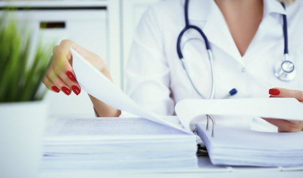 Bureaucracy In The Hospital. Young Female Doctor Work With Stacks Of Files.