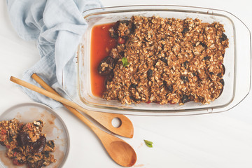 Crumble cake with plum and raspberries in a glass dish. Healthy vegan food concept.