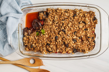 Crumble cake with plum and raspberries in a glass dish. Healthy vegan food concept.