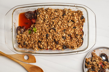 Crumble cake with plum and raspberries in a glass dish. Healthy vegan food concept.