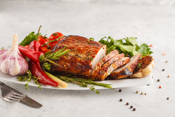 Roasted pork with thyme, rosemary, garlic and tomato sauce on a white dish, white background, copy space.