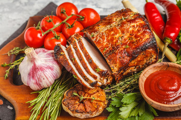 Baked pork with thyme, rosemary, garlic and tomato sauce on wooden board, white background