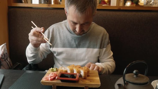 A man learns to use chopsticks for sushi. The man looks at the instructions from the sushi sticks. Hashi, chopsticks ohashi, varibasi - simple wooden hasi
