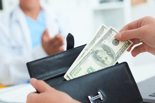 Female patient takes out of her wallet hundred dollar bills to pay for the services of a doctor. Bribery and corruption in Health Care Industry.