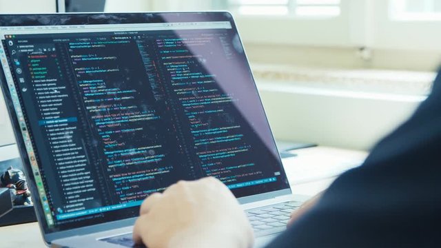 computer programmer sitting in front of a screen coding software