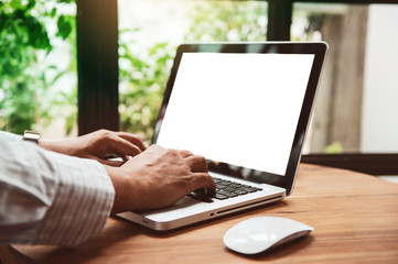 Business man  hands using laptop with blank screen on desk in cafe. instagram style filter photo vintage tone