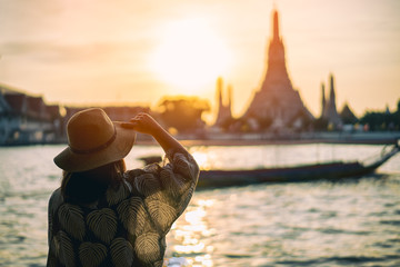 Fototapeta premium Młoda kobieta podróżująca do świątyni Wat Arun Ratchawararam Ratchawaramahawihan w bangkoku, Tajlandia o zachodzie słońca