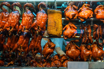 Rows of roast ducks with roast chicken and crispy pork on display at a Chinese restaurant in...
