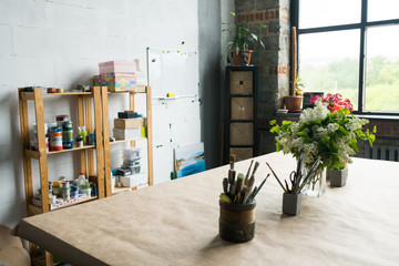 Background shot of creative art space interior table with paintbrushes on it, loft styled workshop,  no people