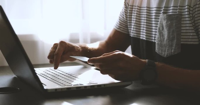online shopping - man entering credit card data in laptop for internet payment