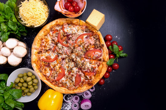 Pizza with meat Vegetables and Spices on a black background with copy space. Top view.