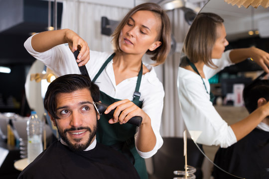 female professional shaving male's hair