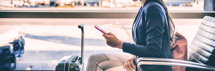 Plane passenger woman waiting for flight departure texting sms message on mobile phone at lounge airport. Businesspeople travel lifestyle panoramic banner.