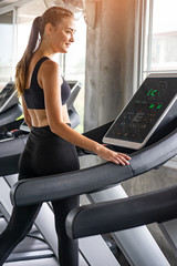Fototapeta na wymiar Cute young woman exercising on treadmill at a gym.Active young woman running on treadmill. smile and funny emotion.