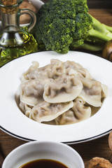 Close up fresh boiled dumplings with hot steams on wood plate. Chinese food on rustic old vintage wooden background.