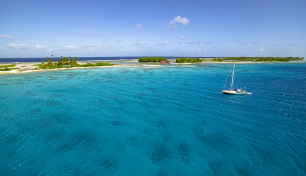 sailing yacht anchoring in the shallow, turquoise lagoon of Fakarava atoll, Tuamotus archipelago, French Polynesia, south pacific