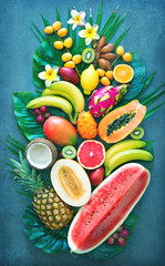 Assortment of tropical fruits with palm leaves and exotic flowers