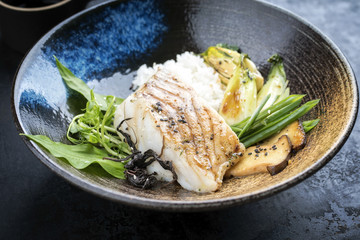 Modern Japanese fried cod fish filet with bok choi and rice as top view in a bowl