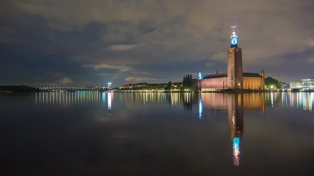 Establishing shot of Stockholm City Hall building at night 4K Time Lapse. Town Hall famous landmark, nobel prize award ceremony. Beautiful calm water reflections, Capital city of Sweden
