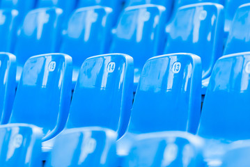 Empty blue plastic seats in the audience.