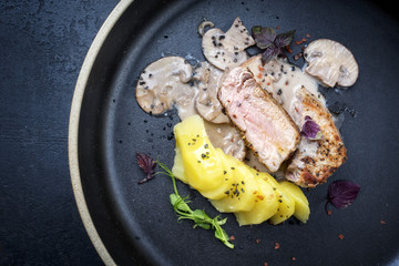 Modern gebratenes Schweine Filet mit Salzkartoffel und Pilzen in Sahnesauce als Draufsicht auf...