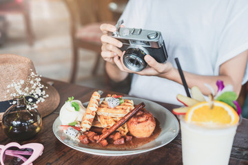 Young woman blogger taking photo of food in cafe