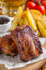 Grilled meat ribs with fried potato slices with barbecue sauce, tasty picnic dish. Food on Board