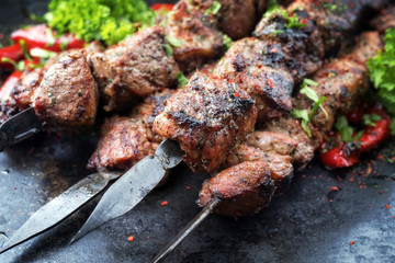 Traditional Russian shashlik on a barbecue skewer with paprika as closeup on an old board