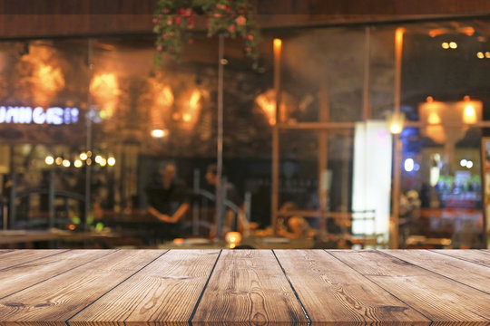 Empty wood table top with blurred light bokeh in night cafe or restaurant background