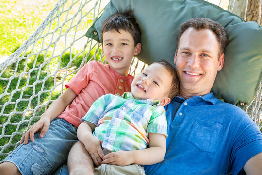 Caucasian Father Relaxing In Hammock with Mixed Race Chinese Sons