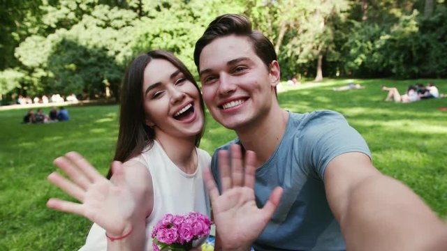 Face young couple in love sitting in the park at sunset makes the selfie smartphone camera nature selfie taking flowers female lifestyle love mobile outdoors phone portrait self together fun girl