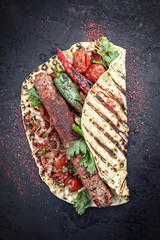 Traditionelles Adana Kebap mit Tomaten und Salat auf einem Fladenbrot mit Textfreiraum 