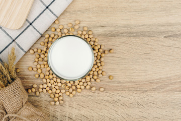 Obraz na płótnie Canvas top view of a glass of soy milk, a pile of soybeans and dried wheat bouquet on the wooden table.
