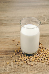 a glass of soy milk and a pile of soybeans on the wooden table.