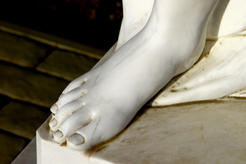 Foot of white beautiful female marble statue close up