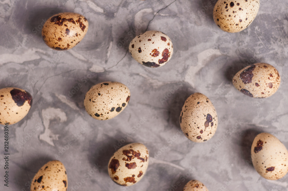 Wall mural Scattered lot of spotted fresh quail eggs on old broken worn gray cement floor