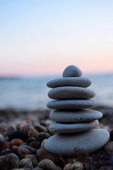 A pile of flat stones on the beach. The sea and sunset in the background