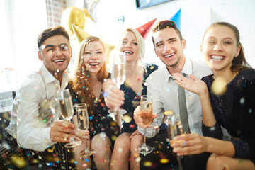 Group of young laughing friends with champagne expressing joy during home birthday party