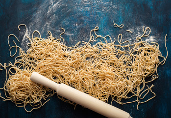 Dried egg noodles. Raw Fresh Spaghetti on blue wooden background