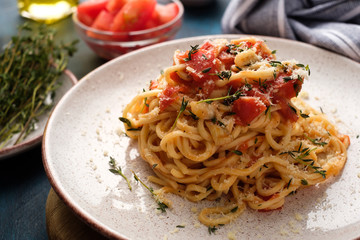 Spaghetti with tomatoes and thyme in a plate on a blue table
