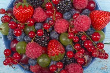 Various summer Fresh berries in a bowl on rustic wooden table. Antioxidants, detox diet, organic fruits. Top view