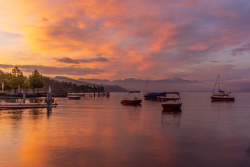 Fototapeta premium Colorful sunrise on the marina of Lausanne on the Lake Leman in summer with the view of the Swiss Alps in background - 1