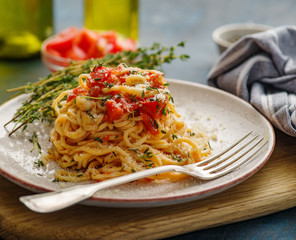 Spaghetti with tomatoes and thyme in a plate on a blue table